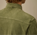 Person wearing a green corduroy shirt with a neutral background