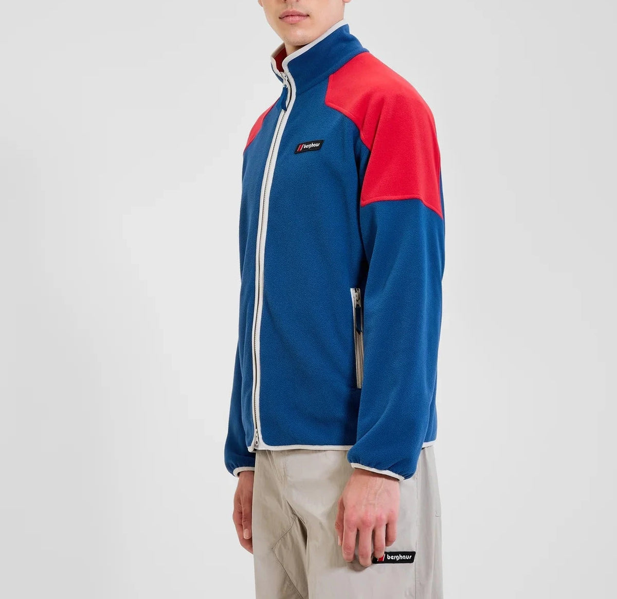Person wearing a blue and red Berghaus flecce jacket on a plain background