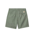 A pair of sage green Carhartt shorts shown from the back, featuring two back pockets and a small signature Carhartt logo patch on the right pocket, set against a solid gray background.