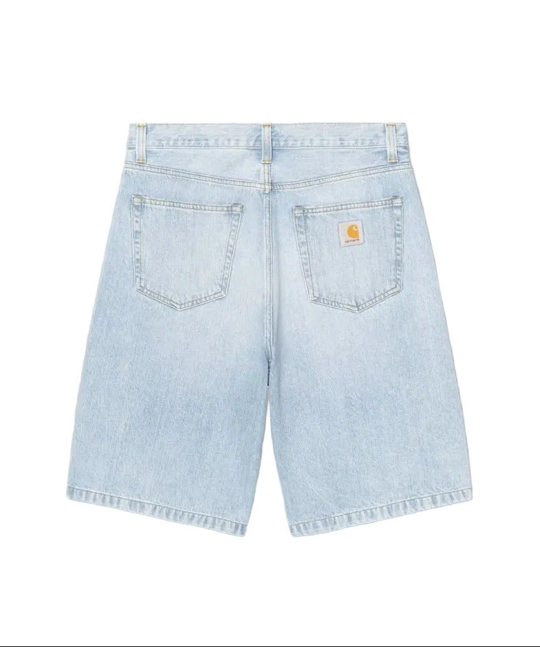 Light wash blue denim shorts shown from the back, featuring two back pockets with a small yellow Carhartt logo patch on the right pocket, set against a plain white background.