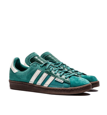 Teal Adidas sneakers with white stripes on a white background