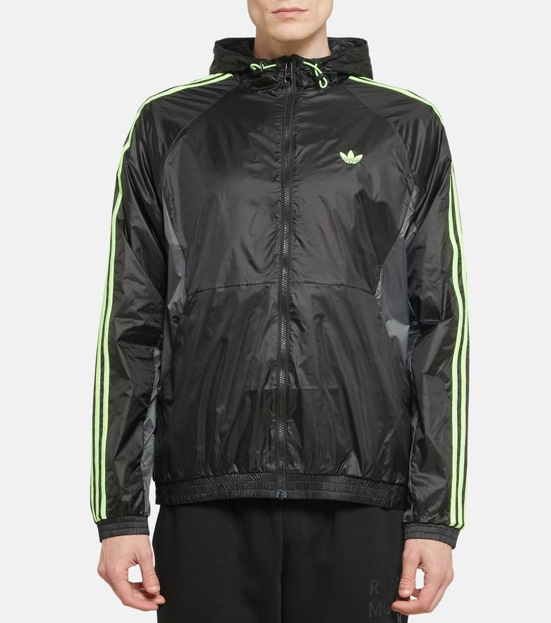 Person wearing a black Adidas jacket with green accents on a white background
