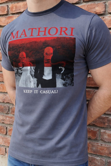 Person wearing a t-shirt with 'Mathori' design and text against a brick wall.