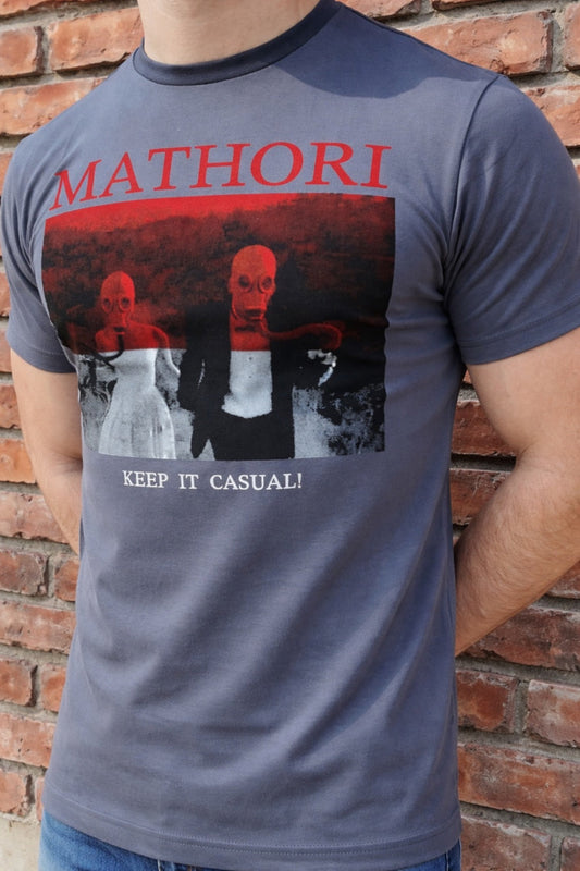 Person wearing a t-shirt with 'Mathori' design and text against a brick wall.