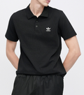 Person wearing a black Adidas polo shirt and pants on a white background