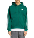 A man wearing a green Adidas full-zip hoodie with white stripes on the sleeves and a white logo on the chest, paired with gray sweatpants, against a plain white background.