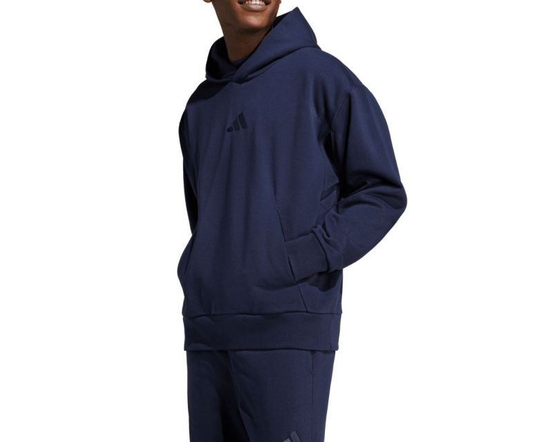 Man wearing a navy blue Adidas hoodie and pants on a white background