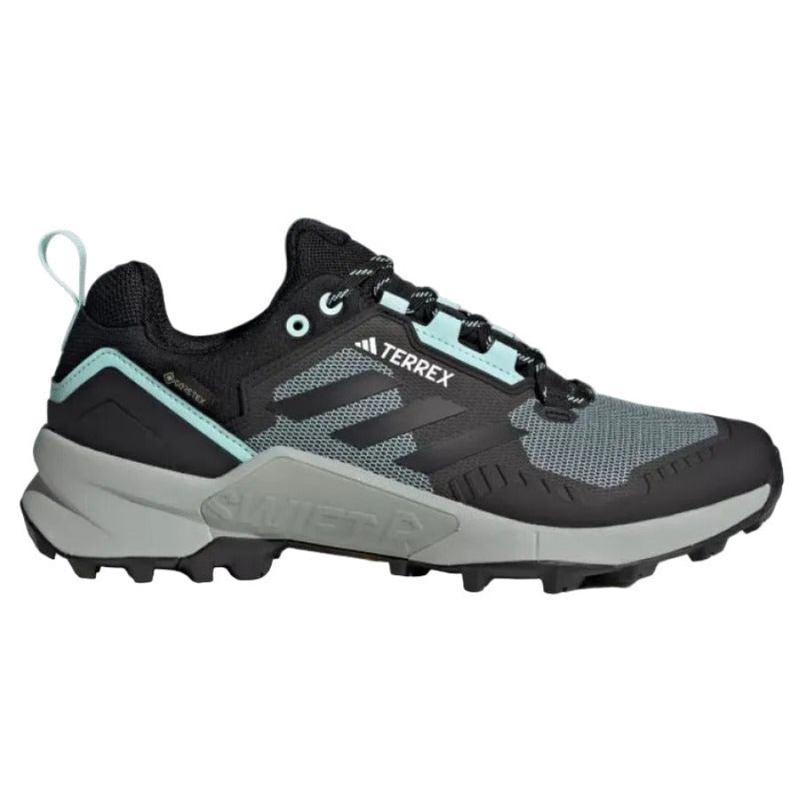Black and gray Adidas Terrex sneaker with teal accents on a light gray background