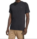 Person wearing a black Adidas t-shirt and beige pants on a white background