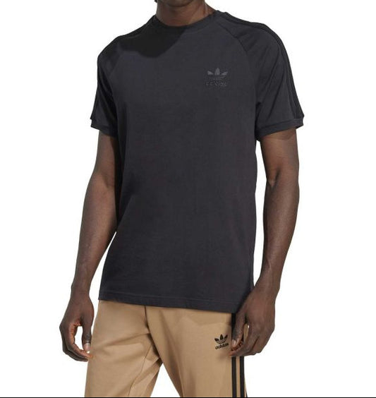 Person wearing a black Adidas t-shirt and beige pants on a white background