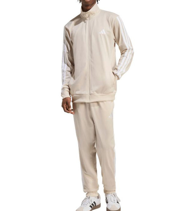 Person wearing a beige tracksuit with Adidas logo on a white background