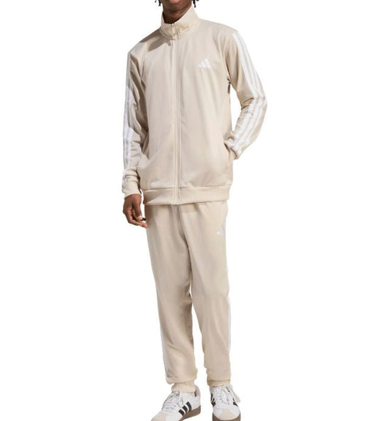 Person wearing a beige tracksuit with Adidas logo on a white background
