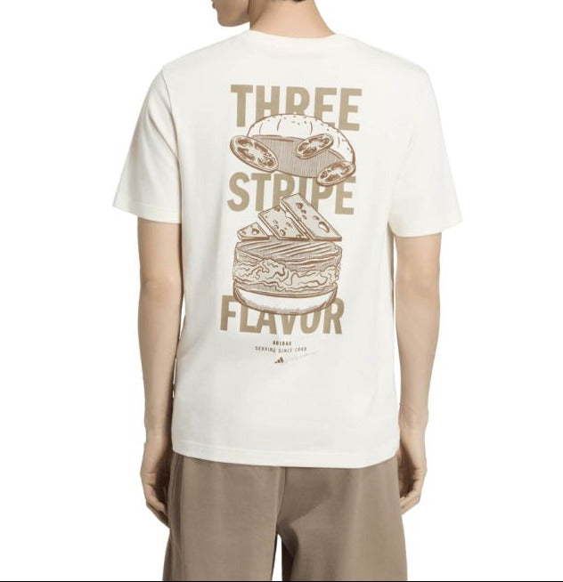 A man viewed from the back wearing a cream-colored t-shirt with a large brown graphic of a sandwich and the text 'THREE STRIPES FLAVOR'.