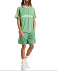 Person wearing a green Adidas outfit on a white background