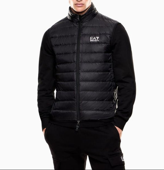 Man wearing a black EA7 puffer jacket with a brand logo on a white background